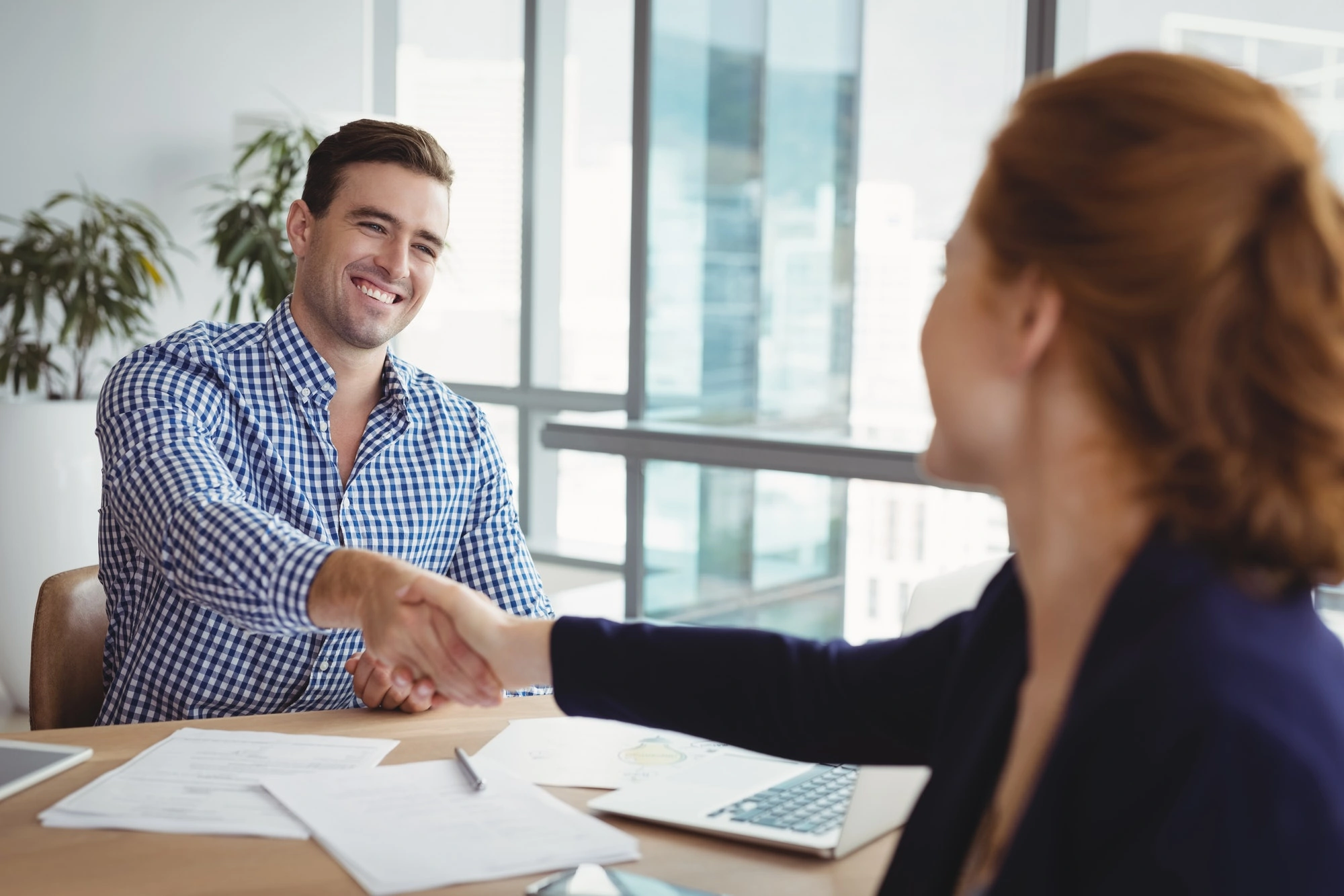 smiling executives shaking hands at desk